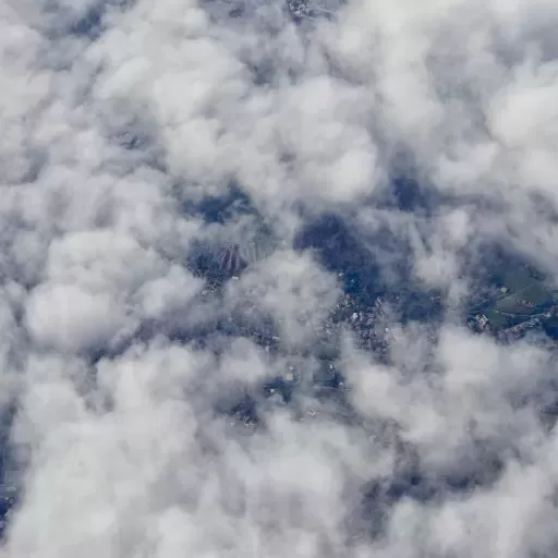 Blick durch lichte Wolkendeck auf Siedlung in Norditalien